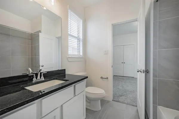a bathroom with a granite countertop sink a toilet and a mirror