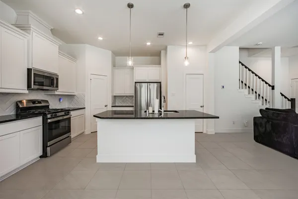 a kitchen with stainless steel appliances granite countertop a sink a stove and a refrigerator