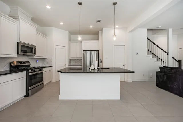 a kitchen with stainless steel appliances granite countertop a sink a stove and a refrigerator