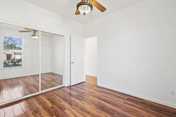 a view of empty room with wooden floor and fan