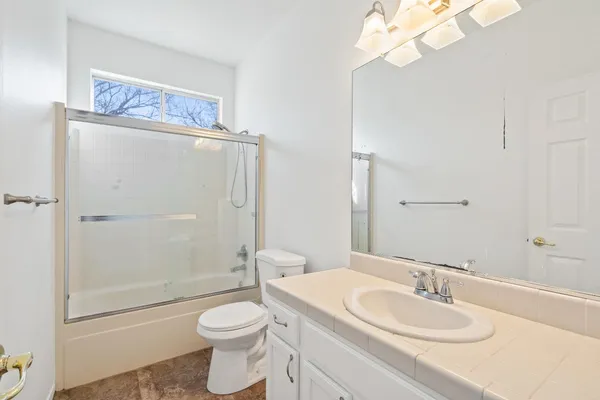 a bathroom with a granite countertop toilet a sink and a mirror