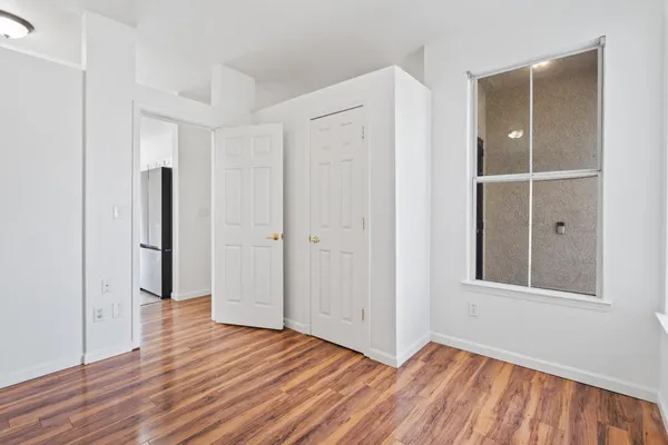 a view of an empty room with wooden floor and closet area