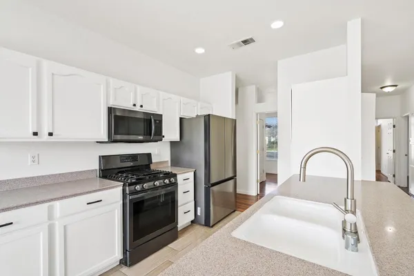 a kitchen with stainless steel appliances kitchen island granite countertop a stove a sink and a refrigerator