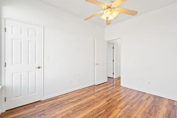 an empty room with wooden floor fan and windows