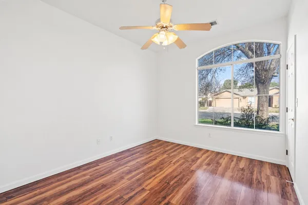 an empty room with a window and wooden floor