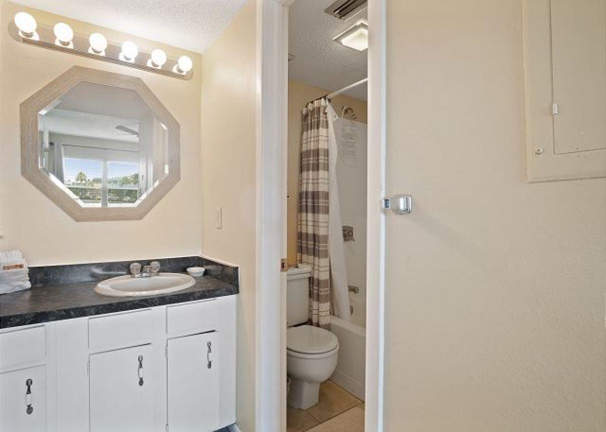 909 Santa Rosa Boulevard, Unit 211 Fort Walton Beach, FL 32548 - Photo 12 of 21 a bathroom with a granite countertop sink a toilet a mirror and shower