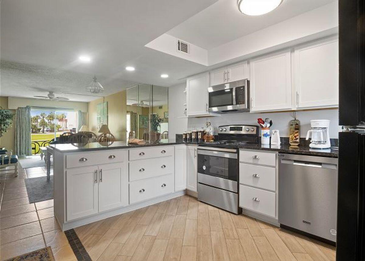 909 Santa Rosa Boulevard, Unit 211 Fort Walton Beach, FL 32548 - Photo 2 of 21 a kitchen with stainless steel appliances granite countertop a stove a sink dishwasher and a microwave oven with white cabinets