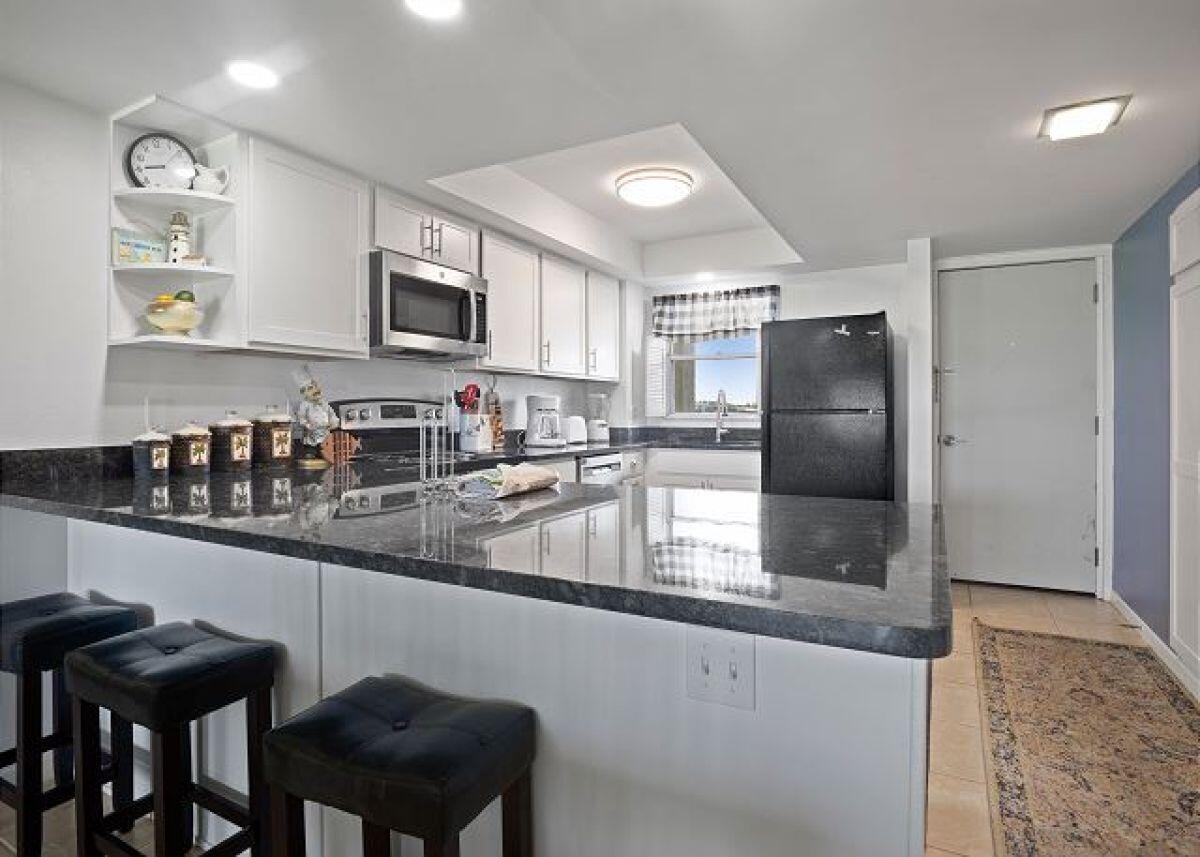 909 Santa Rosa Boulevard, Unit 211 Fort Walton Beach, FL 32548 - Photo 3 of 21 a kitchen with stainless steel appliances granite countertop a refrigerator a sink a stove a dining table and chairs