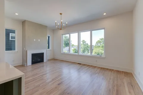 an empty room with wooden floor fireplace and windows