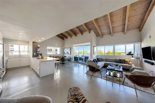a living room with furniture kitchen view and a large window