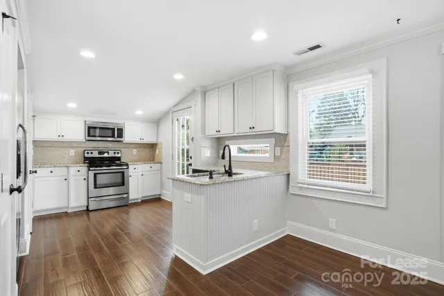 a kitchen with granite countertop a stove top oven and cabinets