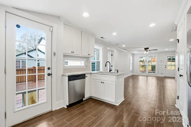 a large white kitchen with lots of counter top space wooden floor and stainless steel appliances