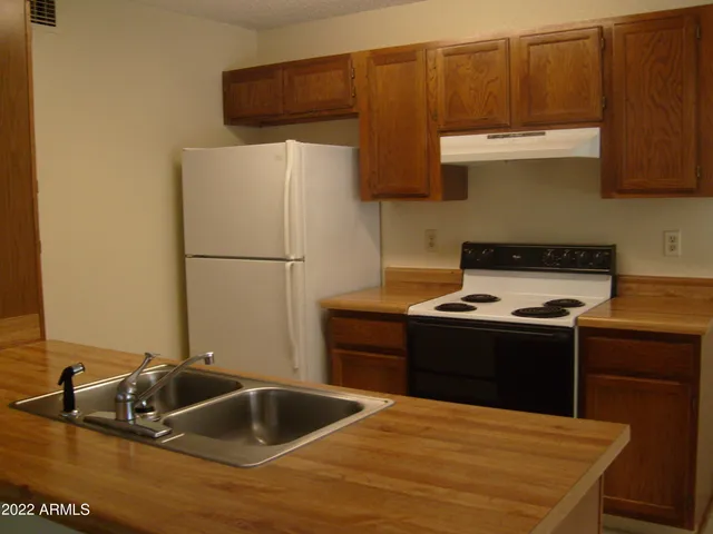 a kitchen with granite countertop a sink and a stove with wooden floor
