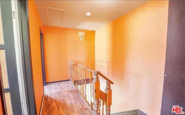 a view of a hallway with wooden floor and a bathroom