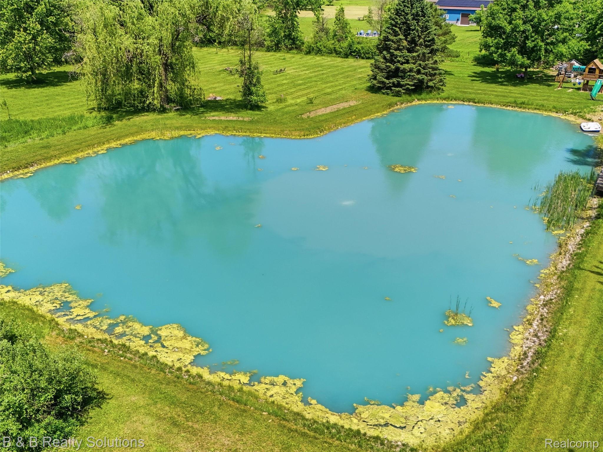 60455 Bates Road New Haven, MI 48048 - Photo 8 of 58 Expansive outdoor space featuring a large, irregularly shaped pond with bright blue water