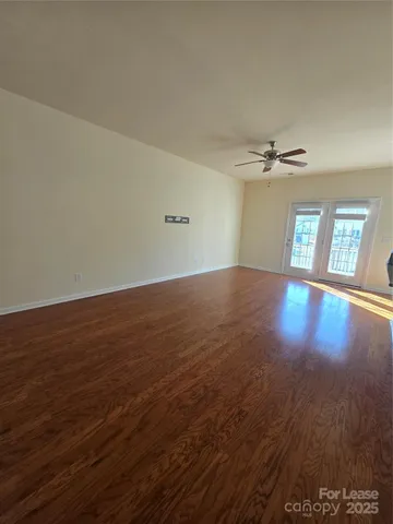 a view of an empty room with window and wooden floor