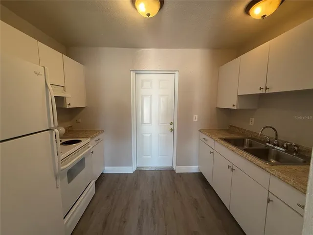 a kitchen with a sink a refrigerator and cabinets