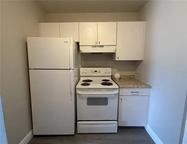 a white refrigerator freezer and a stove sitting inside of a kitchen