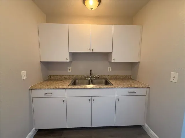 a kitchen with granite countertop a sink a stove and cabinets