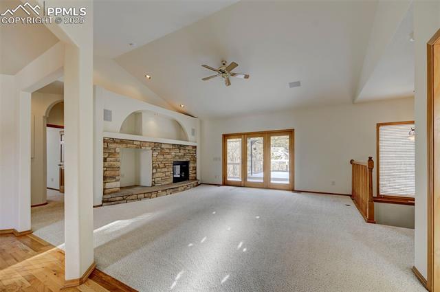 15091 Ridgefield Lane Colorado Springs, CO 80921 - Photo 2 of 35 Unfurnished living room featuring ceiling fan, a fireplace, high vaulted ceiling, and light carpet