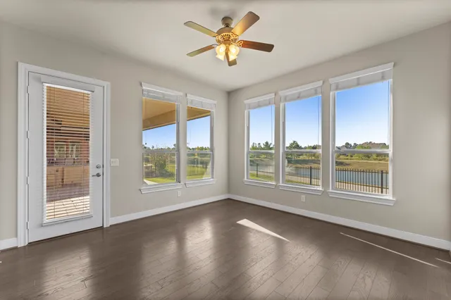 a view of an empty room with a window and wooden floor