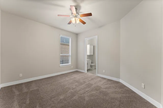 an empty room with closet and a ceiling fan