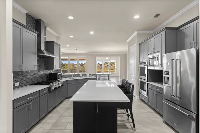 a kitchen with granite countertop a refrigerator a sink a stove top oven a oven with a dining table and chairs