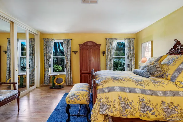a bed sitting in a bedroom next to a window with wooden floor