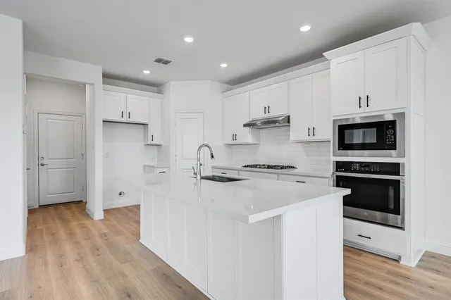a kitchen with stainless steel appliances a refrigerator stove and white cabinets