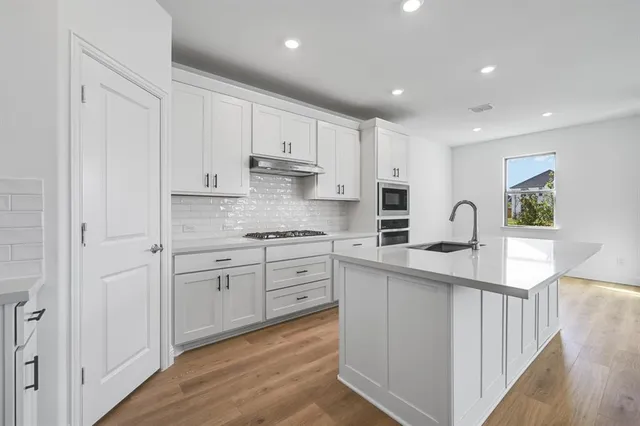 a kitchen with kitchen island white cabinets stainless steel appliances and sink