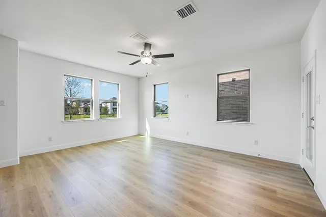 a view of an empty room with window and wooden floor