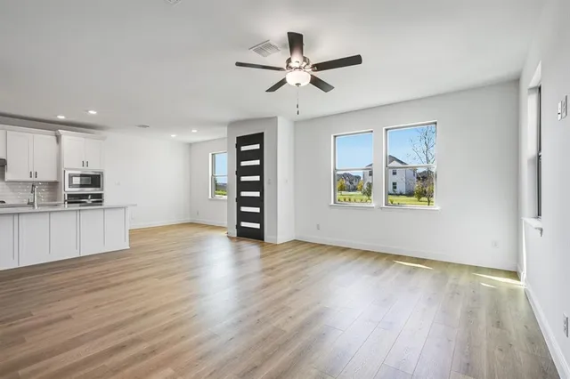 a view of an empty room with window and wooden floor