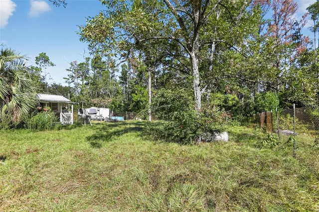 a view of a yard with table and chairs under an umbrella