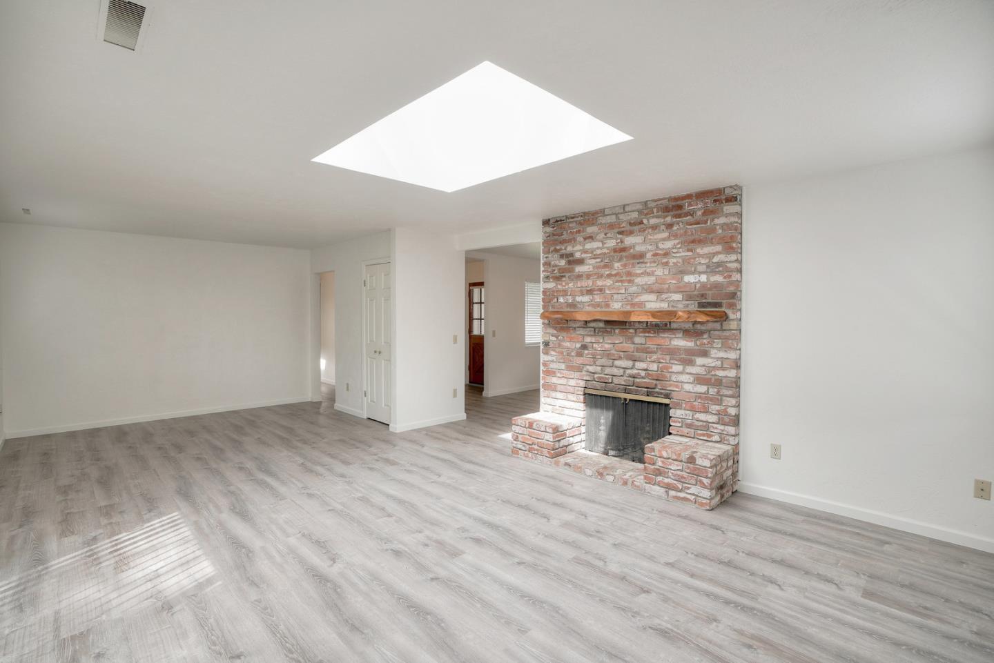 26419 Oliver Road Carmel, CA 93923 - Photo 14 of 35 an empty room with wooden floor fireplace and windows