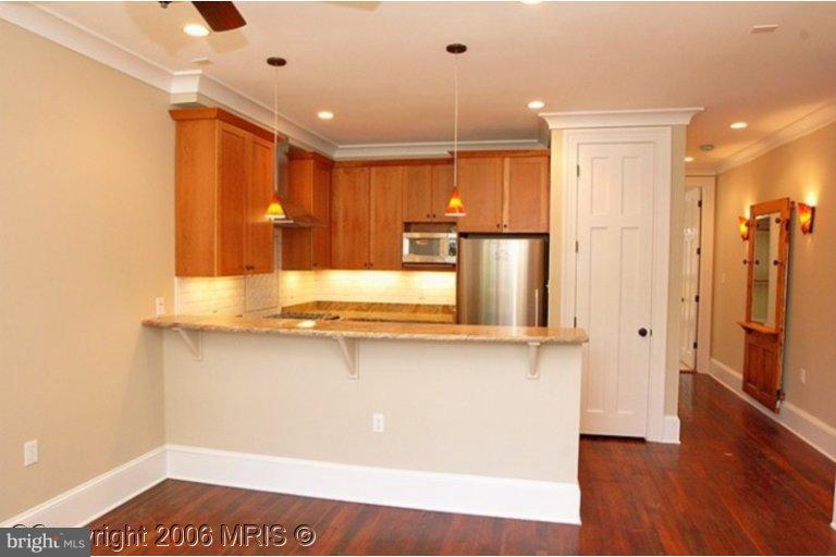 a view of a kitchen with kitchen island a sink wooden floor and stainless steel appliances