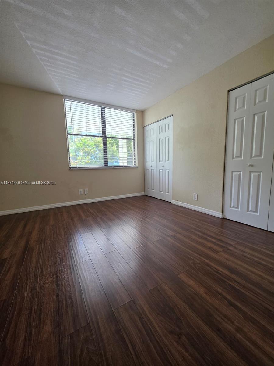 20200 West Country Club Drive, Unit 104 Aventura, FL 33180 - Photo 20 of 43 an empty room with wooden floor and windows