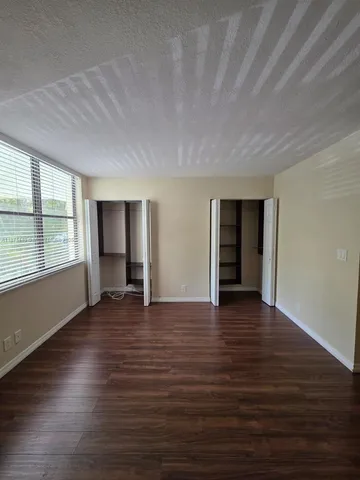 a view of an empty room with wooden floor and closet