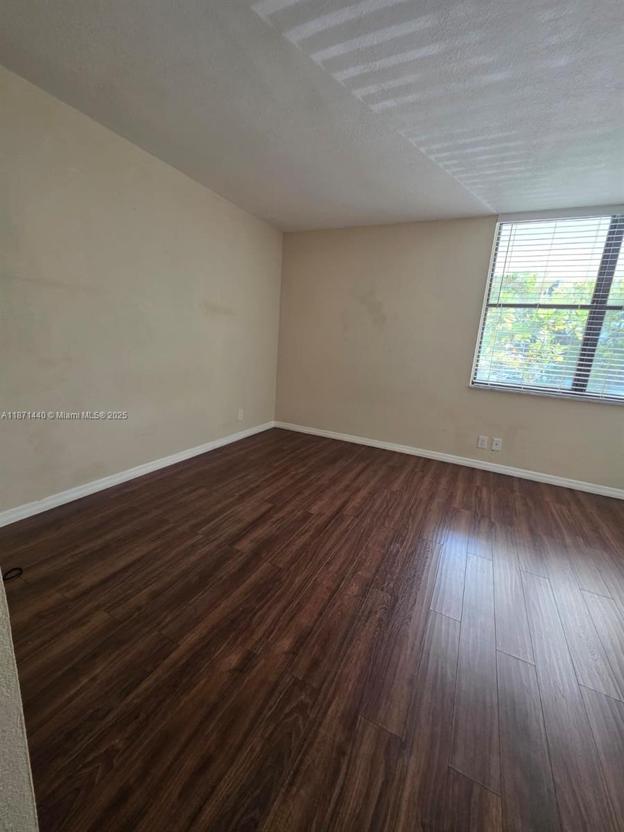 20200 West Country Club Drive, Unit 104 Aventura, FL 33180 - Photo 30 of 43 a view of an empty room with wooden floor and a window