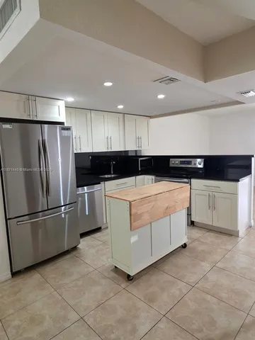 a kitchen with stainless steel appliances kitchen island granite countertop a refrigerator and a sink