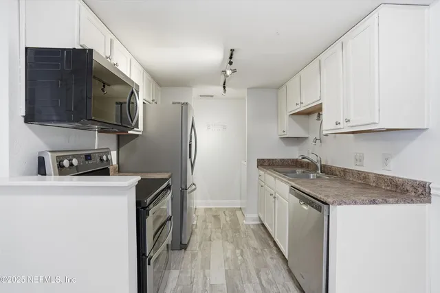 a kitchen with stainless steel appliances granite countertop a refrigerator a stove top oven a sink and dishwasher