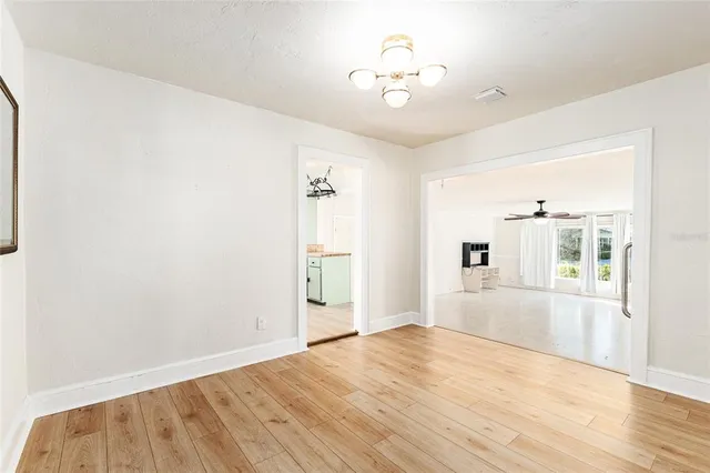a view of a hallway with wooden floor and a bathroom