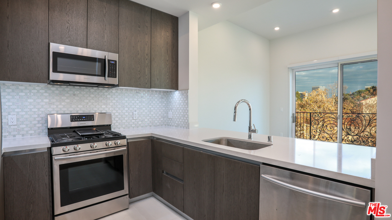 909 Le Doux Road, Unit 403 Los Angeles, CA 90035 - Photo 9 of 28 a kitchen with granite countertop a stove and a microwave