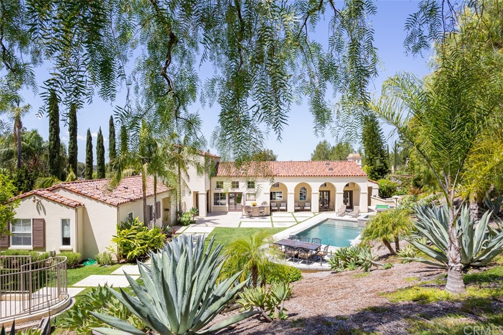 1785 North Kimbark Lane Orange, CA 92869 - Photo 1 of 35 a view of a white house with a large tree and lawn chairs next to a yard