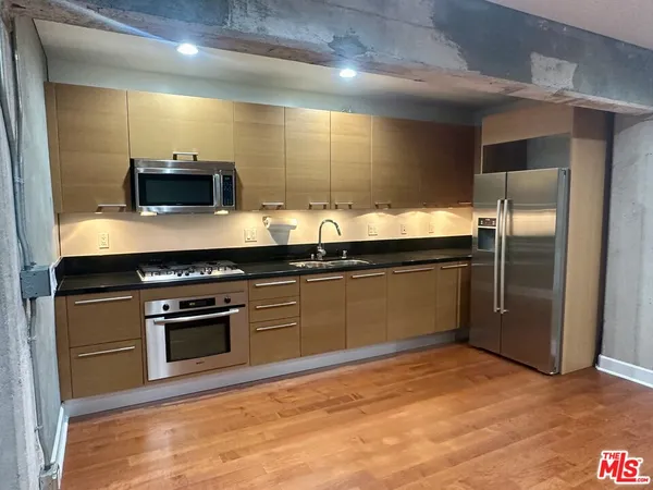 a kitchen with stainless steel appliances kitchen island granite countertop a sink and a stove