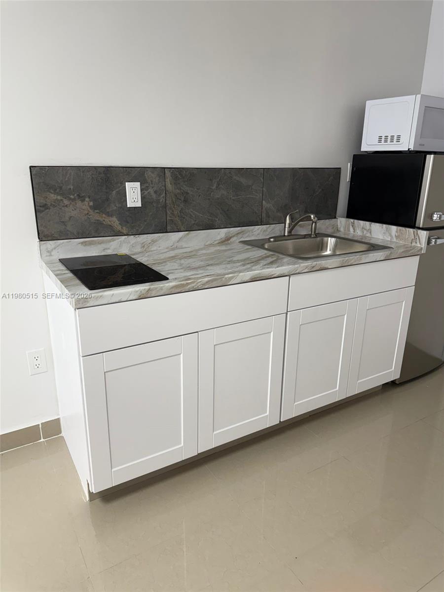 4700 Southwest 2nd Terrace, Unit 1 Miami, FL 33134 - Photo 2 of 8 a kitchen with granite countertop white cabinets and white appliances