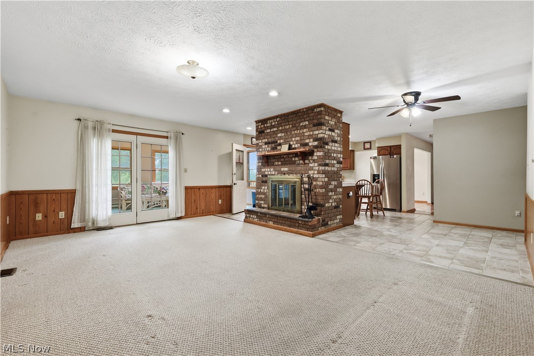 1835 Lynn Road Kent, OH 44240 - Photo 8 of 49 Spacious living area featuring a brick fireplace, French doors, wood paneling, and a ceiling fan