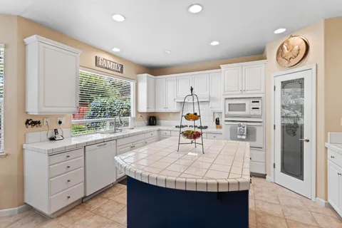 a kitchen with granite countertop a sink a stove refrigerator and cabinets