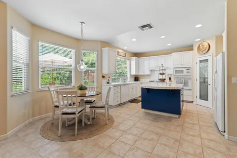 a kitchen with stainless steel appliances kitchen island granite countertop a stove a sink a table and chairs