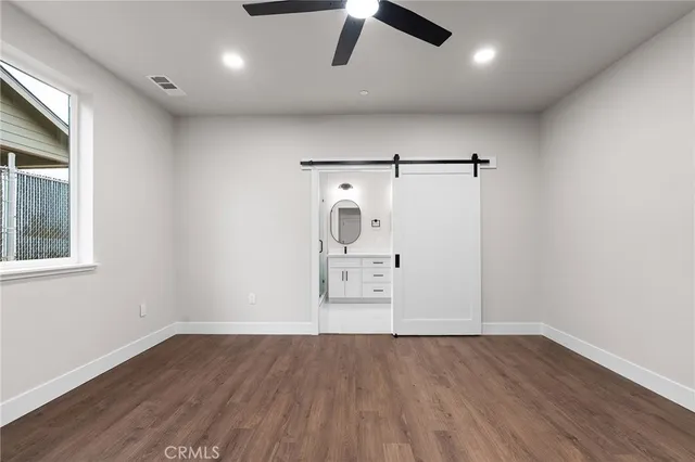 an empty room with wooden floor cabinet and windows