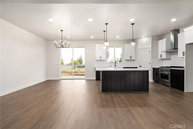 a large kitchen with a large counter top a sink a window and stainless steel appliances